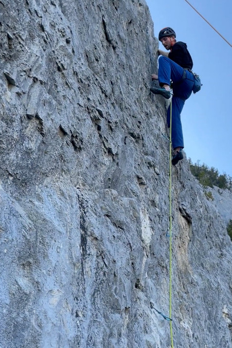 Climber ascending a rockclimbing route with a high left step.