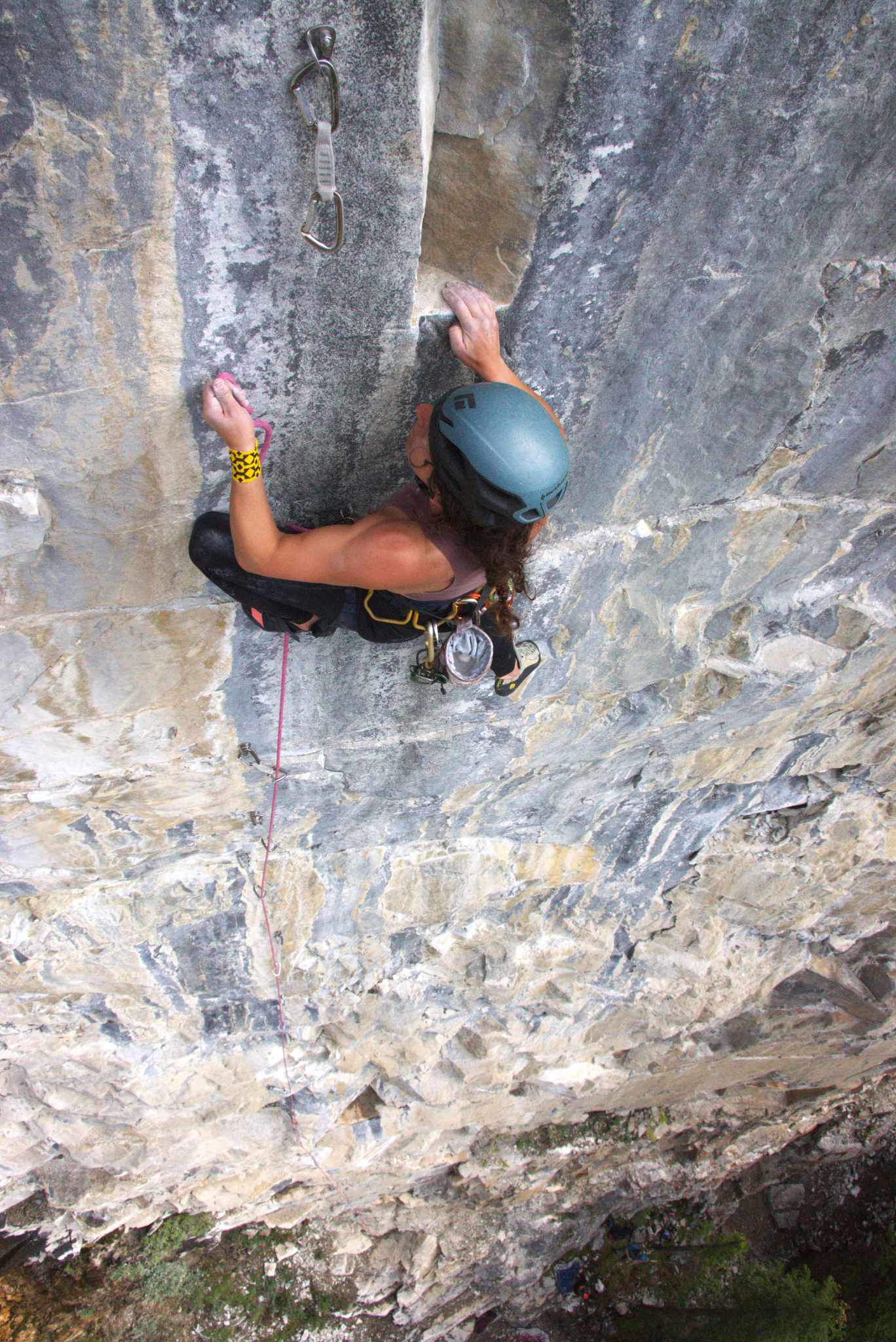 A climber reaches to complete a clip into a quickdraw.