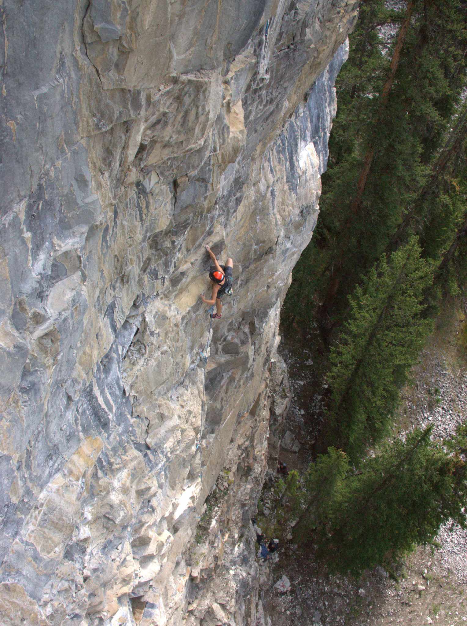 A climber is seen ascending a very tall cliff.