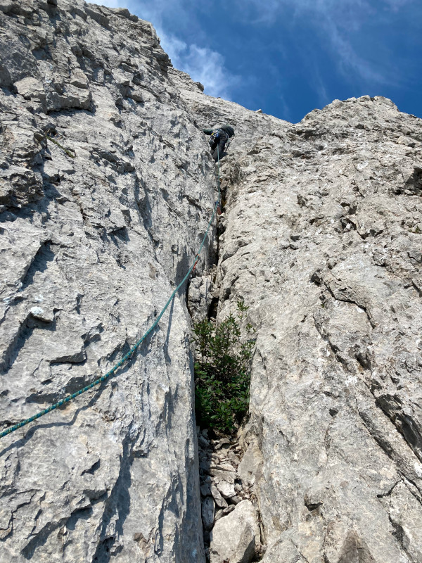 A climber ascending above a rough limestone crack.