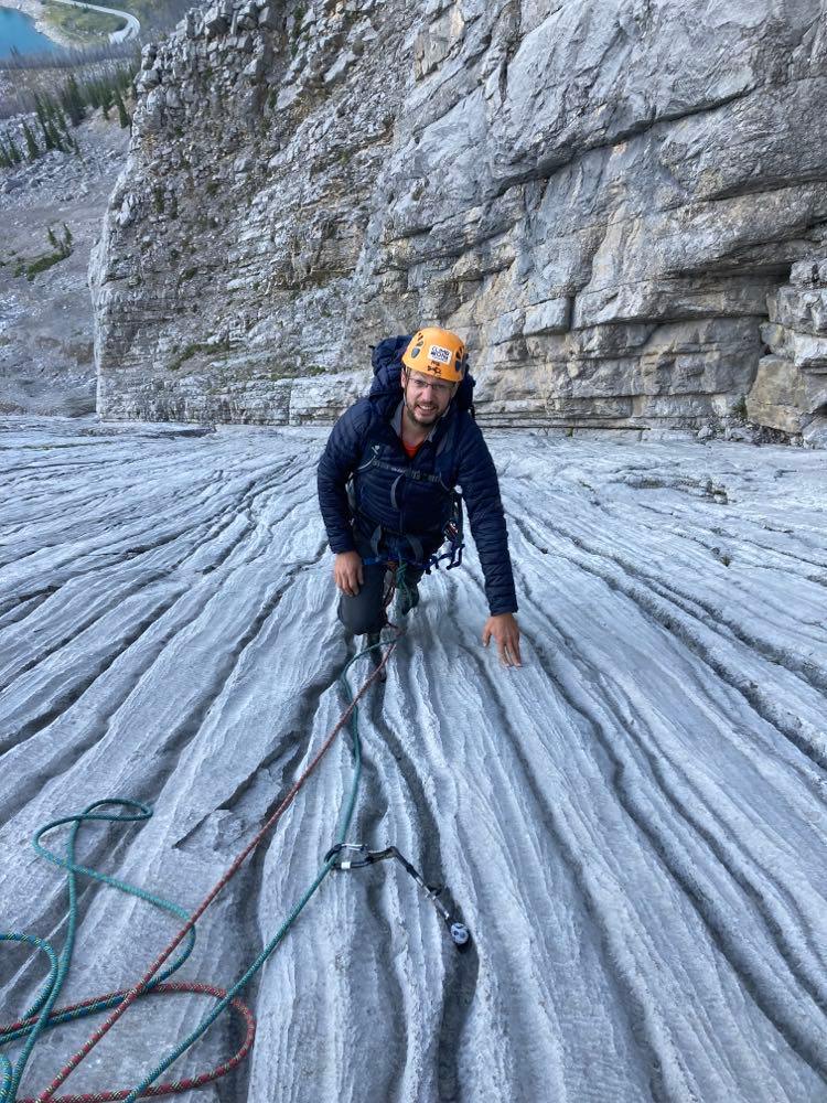 A climber is ascending a rock face and is near their climbing partner.